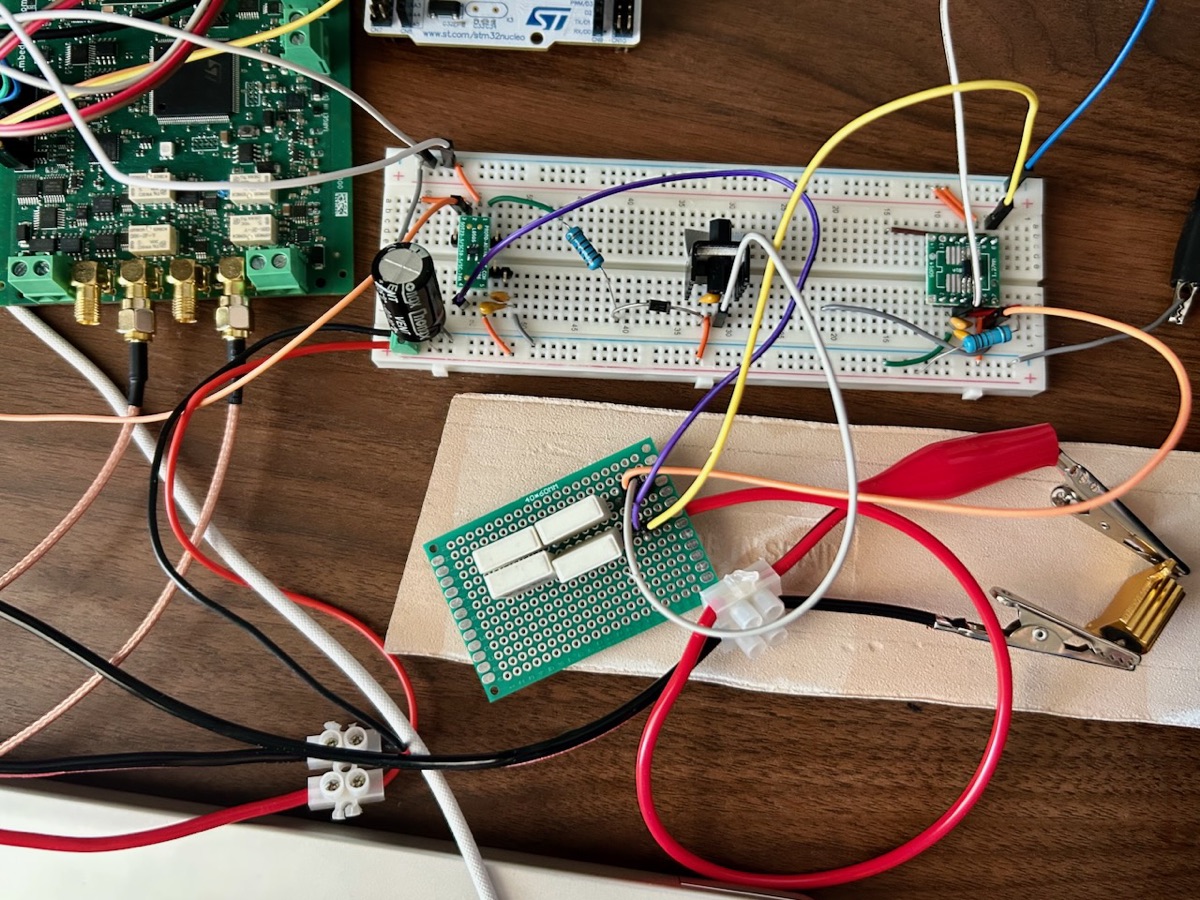 The solar simulator bench: BenchPod at left with its SMA analog connectors, the breadboard carrying the TLV9152 op-amp, the heatsinked IRLZ44N pass MOSFET and the INA282 current-sense amplifier, and the four series shunt resistors on perfboard below